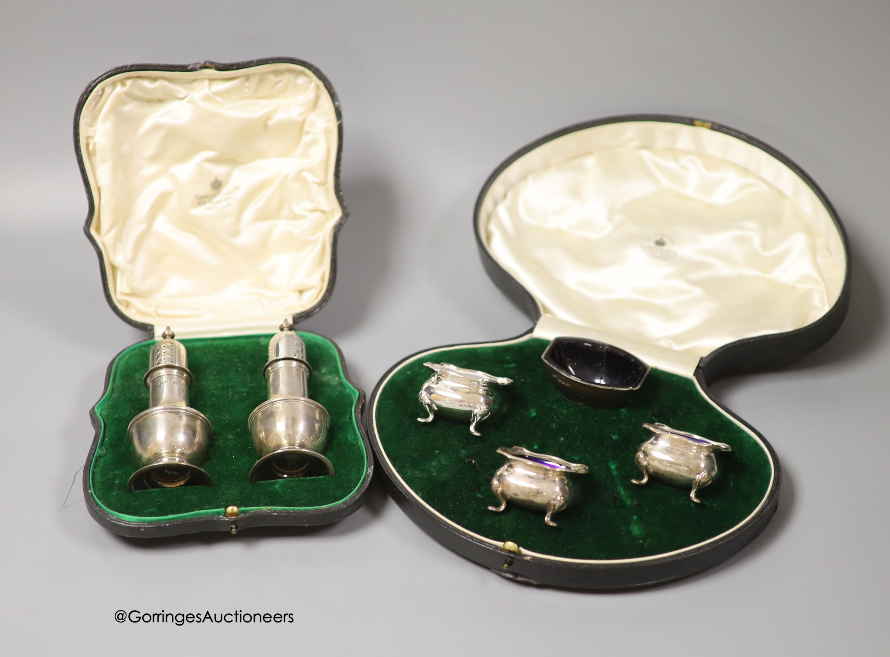 A cased pair of George V silver pepperettes, Mappin & Webb, London, 1913, 11.3cm and a cased harlequin four piece silver condiment set.